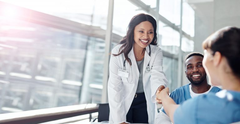 Happy doctors and hospital employees shaking hands in a meeting after discussing a recent EHR Electronic Health Record implementation