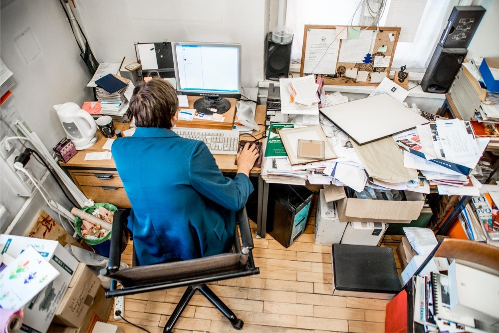 remote worker at a computer desk piled high with paperwork