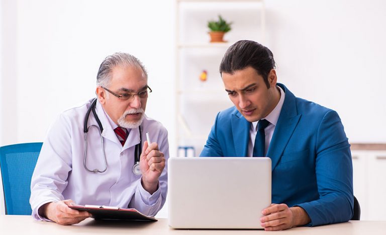 Healthcare professionals and administrators collaborate over patient data on a computer.