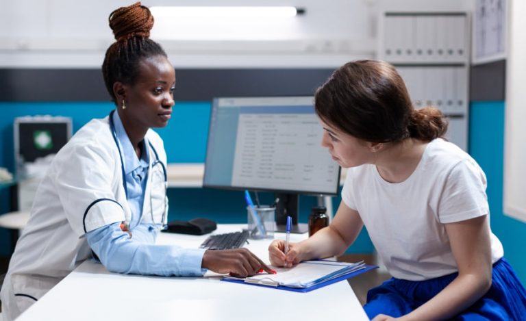 Healthcare professional listening to a patient who is filling out a form.